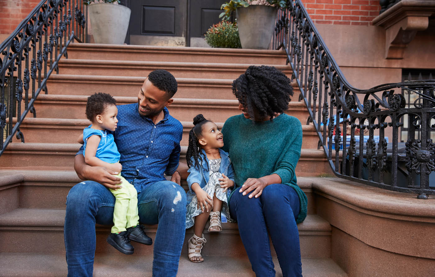 A family sitting on the steps of their city home - get peace of mind when you work with Rest Easy Pest Control.