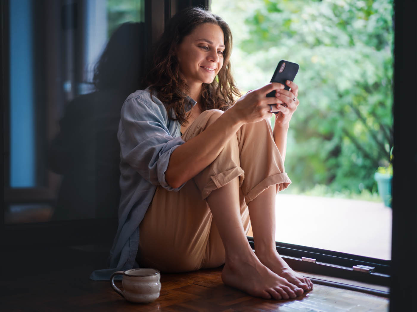 A woman sitting next to her window - contact Rest Easy Pest Control today for wildlife removal and experience peace of mind.